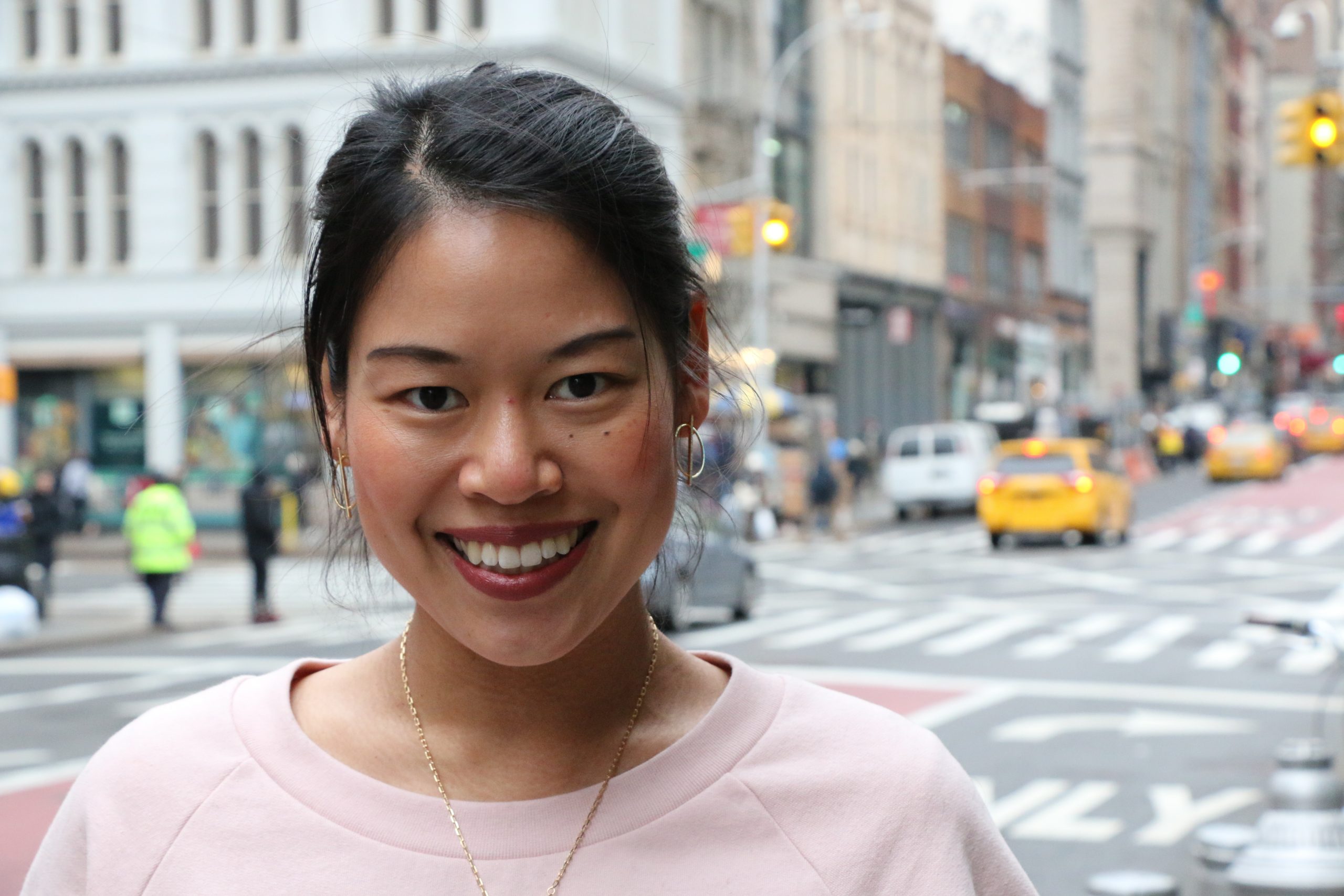 Sophie Chung standing at the corner of a busy intersection in New York City