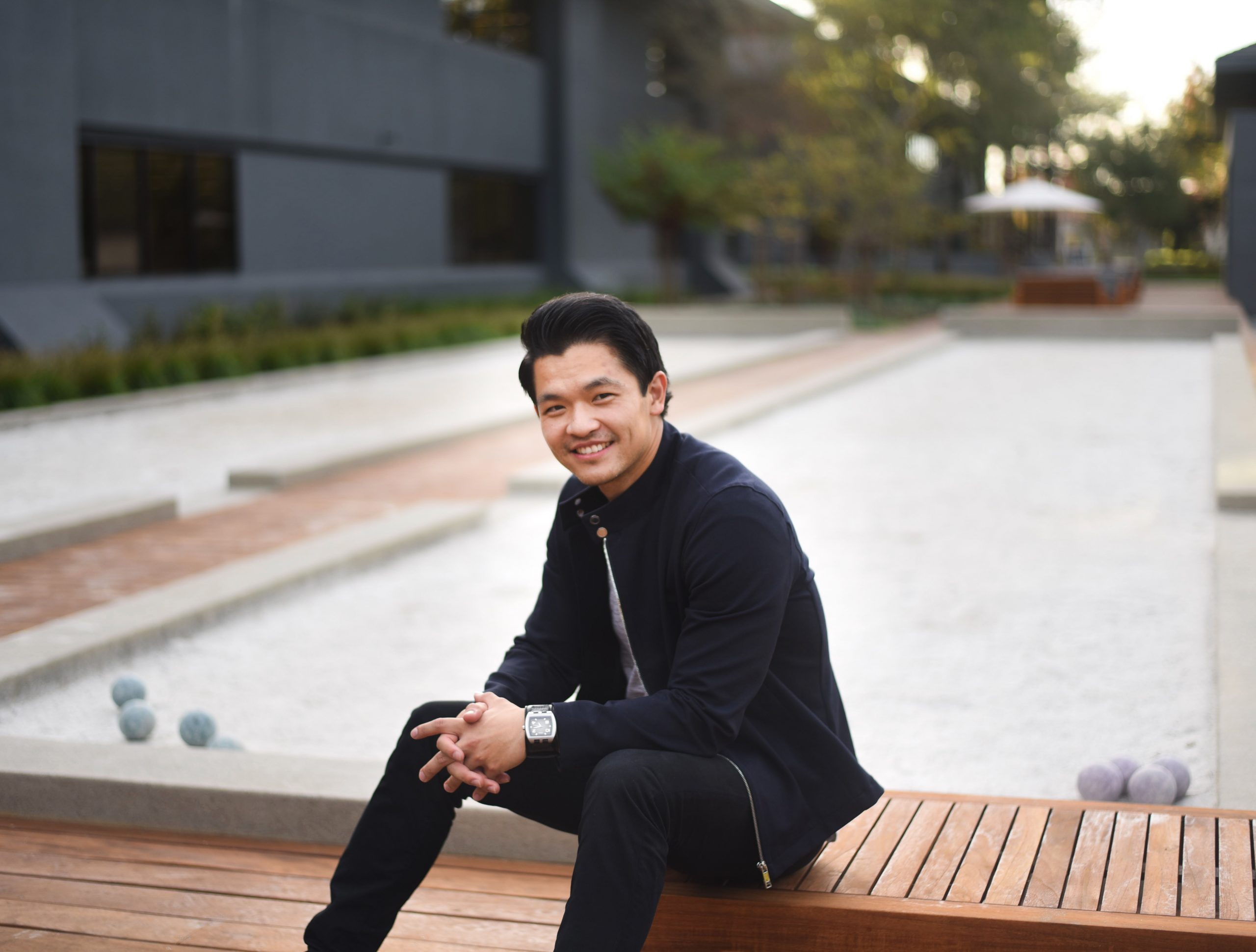 Han Jin sitting on bench smiling into the camera